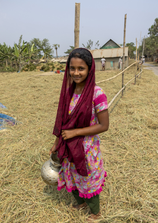 Bangladeshi girl looking at rice crop drying on the road, Chittagong Division, Bijoynagar, Bangladesh
