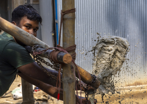 Bangladeshi man using a water pump with muddy water, Chittagong Division, Comilla, Bangladesh