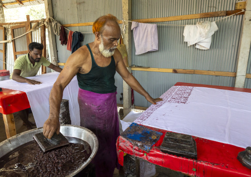 Bangladeshi man stamping wax on a cloth in a batik factory, Chittagong Division, Comilla, Bangladesh