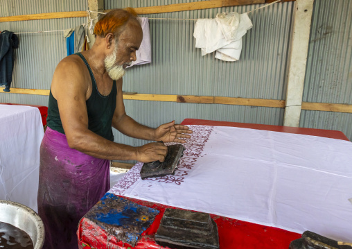 Bangladeshi man stamping wax on a cloth in a batik factory, Chittagong Division, Comilla, Bangladesh