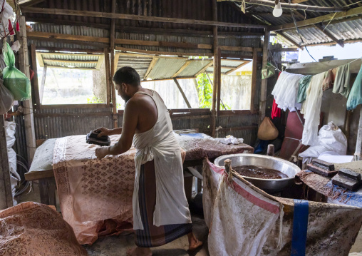 Bangladeshi man stamping wax on a cloth in a batik factory, Chittagong Division, Comilla, Bangladesh