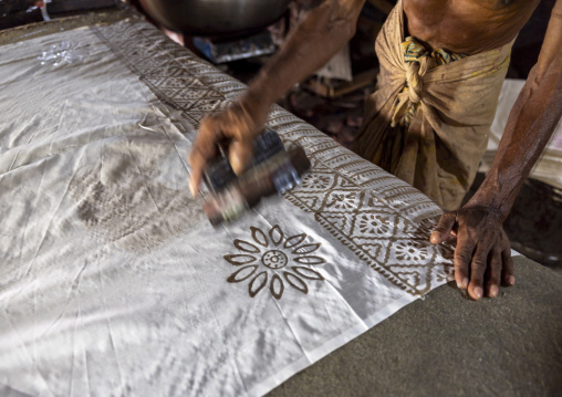 Bangladeshi man stamping wax on a cloth in a batik factory, Chittagong Division, Comilla, Bangladesh