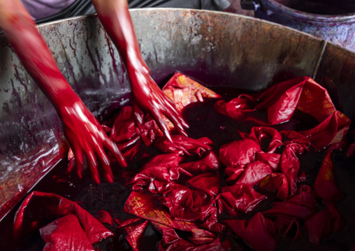 Bangladeshi man dyeing fabrics in red in a batik factory, Chittagong Division, Comilla, Bangladesh