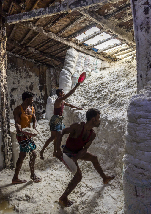 Bangladeshi men pick up salt in a warehouse, Chittagong Division, Chittagong, Bangladesh