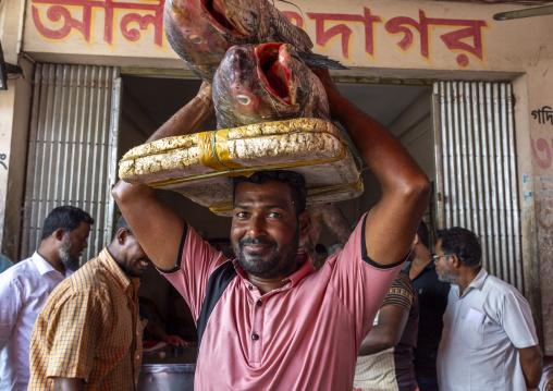 Bangladeshi man carrying big fishes on his head, Chittagong Division, Chittagong, Bangladesh