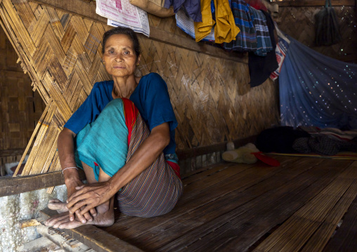 Portrait of a Tanchangya woman inside her house on a bamboo bed, Chittagong Division, Bandarban, Bangladesh