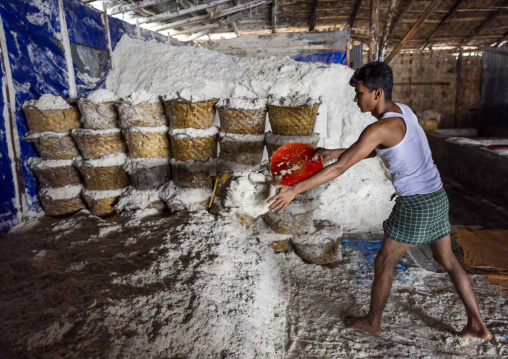 Bangladeshi man picks up salt in a warehouse, Chittagong Division, Chittagong, Bangladesh