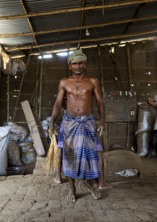 Bangladeshi worker putting dried tobacco leaves in grinder, Rangpur Division, Rangpur, Bangladesh