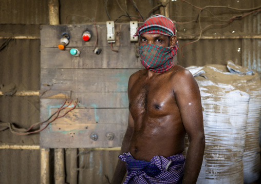 Bangladeshi worker putting dried tobacco leaves in grinder, Rangpur Division, Rangpur, Bangladesh