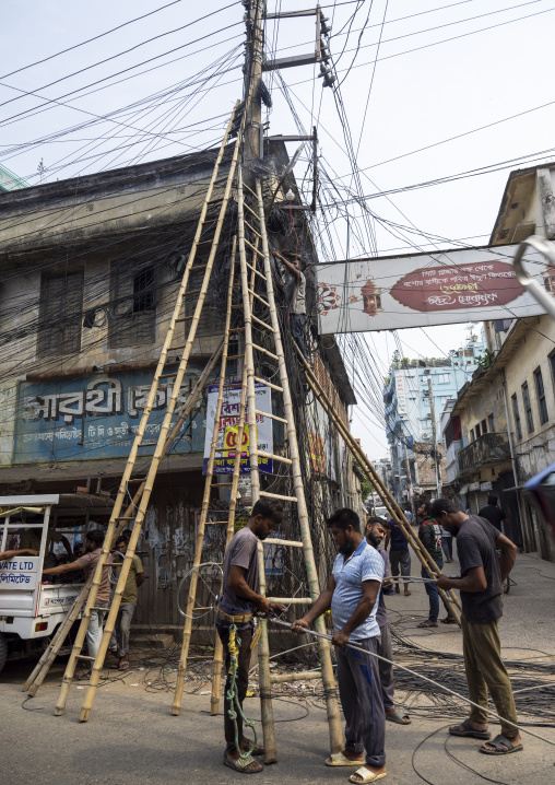 Man fixing tngled wires hanging on electricity pole, Khulna Division, Jessore, Bangladesh