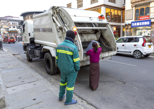 Bhutanese woman putting trashes in a garbage truck, Chang Gewog, Thimphu, Bhutan