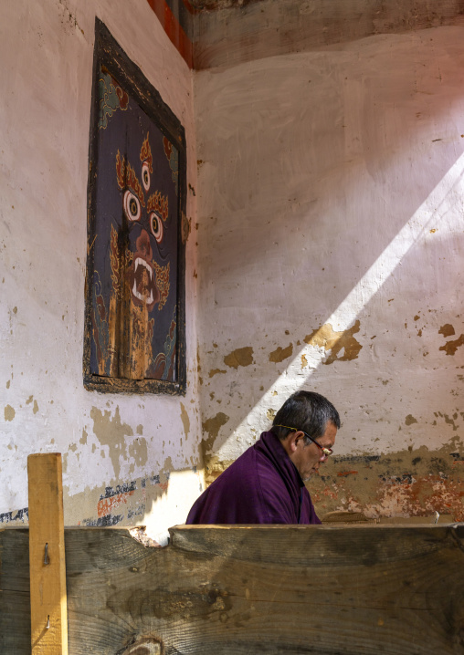 Bhutanese man reading in Jamphel Lhakhang, Chhoekhor Gewog, Bumthang, Bhutan