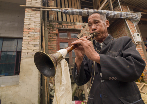Man playing trumpet duriong a funeral procession, Yuanyang, Yunnan province, China