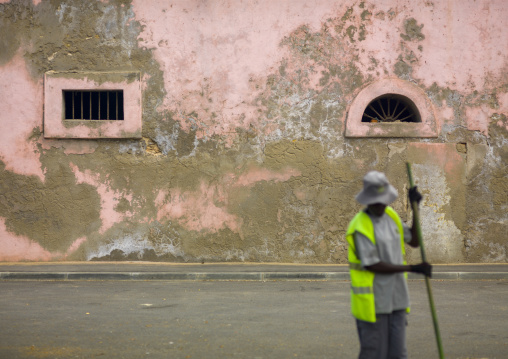 Man with hat raking up in the street, Benguela Province, Benguela, Angola