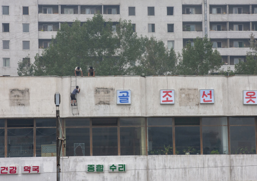 Men fixing korean letters on a wall, Directly governed city, Pyongyang, North Korea