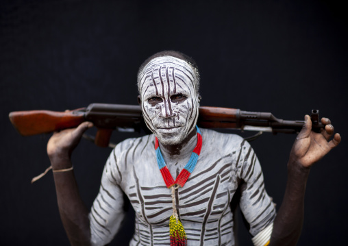 Karo man tribe with white painted chest and kalashnikov, Omo valley, Korcho, Ethiopia