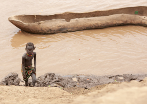 Young Dassanech girl near a pirogue on omo river, Omo valley, Omorate, Ethiopia
