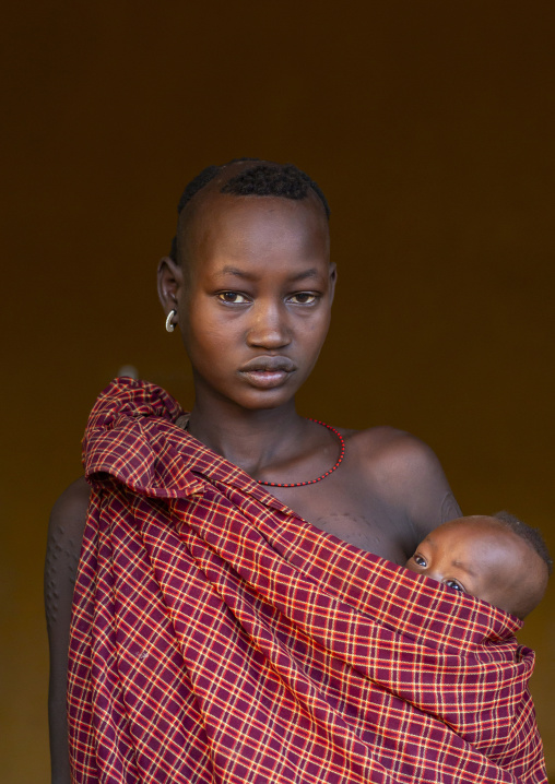 Portrait of a Bodi tribe mother carrying her baby, Hana Mursi, Omo valley, Ethiopia