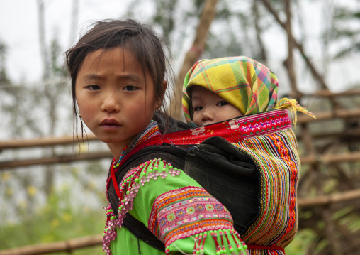 Flower Hmong girl carrying her baby sister on her back, Lao Cai province, Sapa, Vietnam