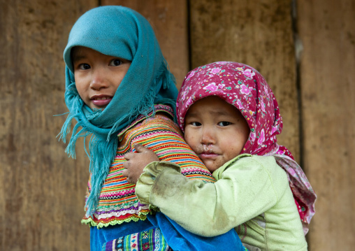 Flower Hmong girl carrying a younger one on her back, Lao Cai province, Sapa, Vietnam