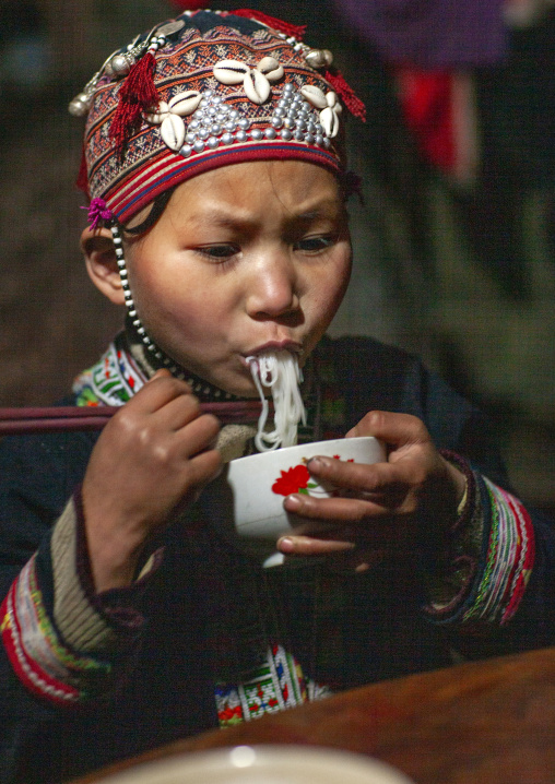 Red dzao girl eating noodles, Lao Cai province, Sapa, Vietnam