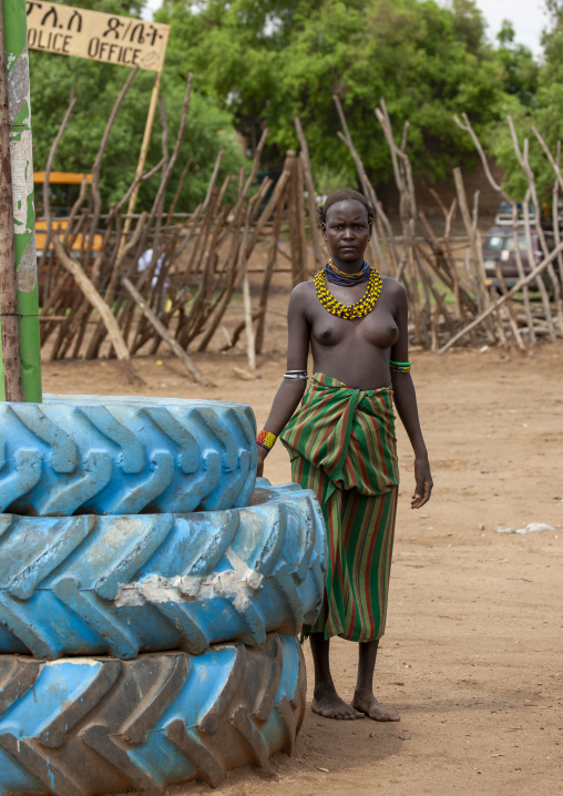 Portrait of a young Dassanech tribe girl next to truck tires, Omorate, Omo valley, Ethiopia
