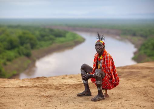 Karo tribe man sitting in front of Omo river, Omo valley, Korcho, Ethiopia