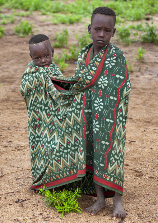Portrait of Karo tribe kids wrapped up in a shared blanket, Korcho, Omo valley, Ethiopia