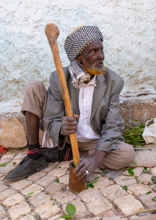Old man without teeth crashing qat to chew In the street, Harari Region, Harar, Ethiopia