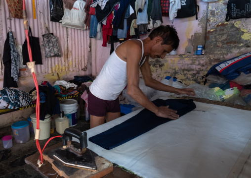Laundry Worker ironing in Dhobi Ghat, Maharashtra state, Mumbai, India
