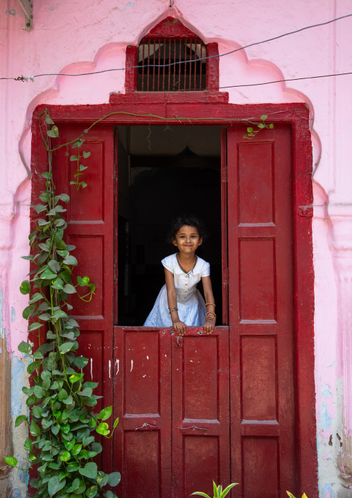 Indian girl standing in a red door in old Delhi, Delhi, New Delhi, India