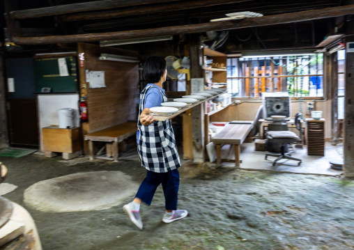 Artisan carrying plates in Genemongama porcelain atelier, Kyushu region, Arita, Japan