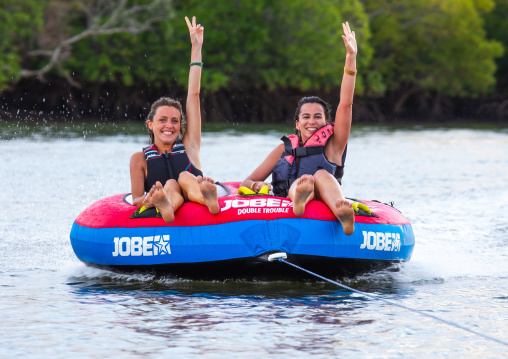 Two young women enjoying donut ride on the sea, Lamu County, Lamu, Kenya