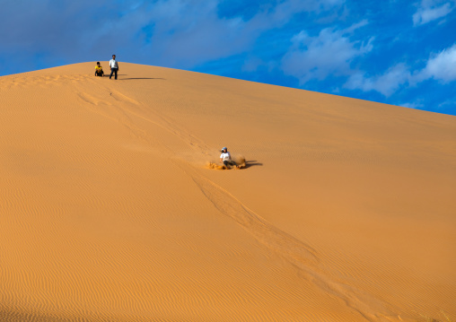 Tourist making sandboarding in the Rub al Khali dunes desert, Najran Province, Thar, Saudi Arabia
