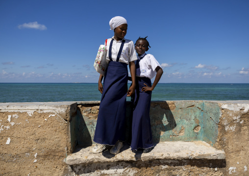 Girls standing on a bench in front of the sea, Nampula Province, Island of Mozambique, Mozambique