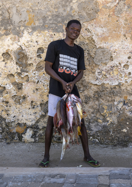 Young man with fresh fishes in the street, Nampula Province, Island of Mozambique, Mozambique