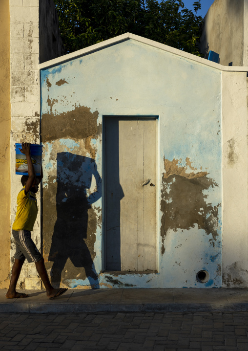 Boy carrying a bucket on his head in the street, Nampula Province, Island of Mozambique, Mozambique