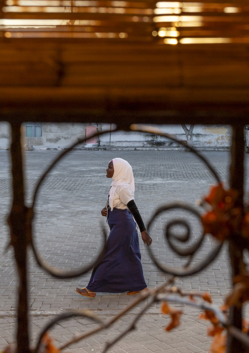 Girl walking in the street seen throught wrought iron, Nampula Province, Island of Mozambique, Mozambique