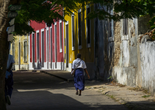 Girl walking along colorful old houses, Nampula Province, Island of Mozambique, Mozambique