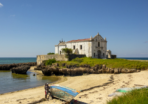 Men fixing a boat in front of the Chapel of Santo Antonio, Nampula Province, Island of Mozambique, Mozambique