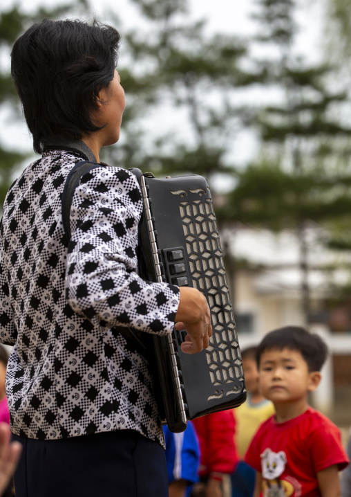 Teacher playing accordion for gymnastics at school, South Hamgyong, Hamhung, North Korea