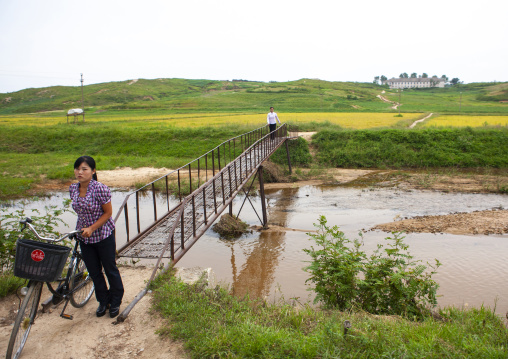 North Korean woman with a bicycle crossing a bridge, North Hwanghae, Kaesong, North Korea