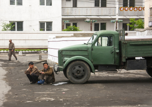 North korean men resting in front of a green truck, South Pyongan, Nampo, North Korea
