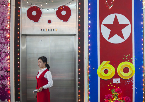 Saleswoman in a clothes shop decorated for the 60th anniversary of the regim, DGC, Pyongyang, North Korea