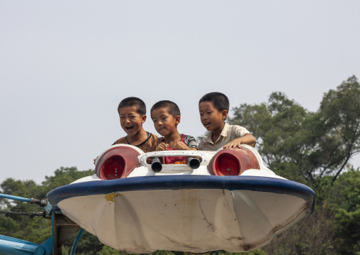 Children having fun on a flying saucer attraction in Taesongsan funfair, DGC, Pyongyang, North Korea