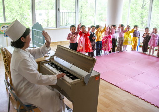 Nurse playing organ to children in an orphanage, South DGC, Nampo, North Korea