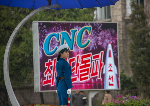 Traffic security officer in blue uniform in front of a CNC billboard, DGC, Pyongyang, North Korea