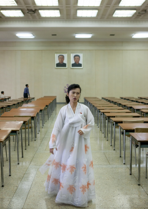 Woman in Grand people's study house below the official portraits of the Leaders, DGC, Pyongyang, North Korea