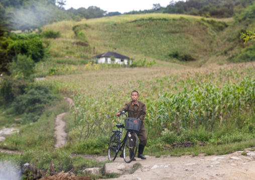 North Korean soldier pushing his bicycle in the countryside, North Hamgyong, Jung Pyong Ri, North Korea