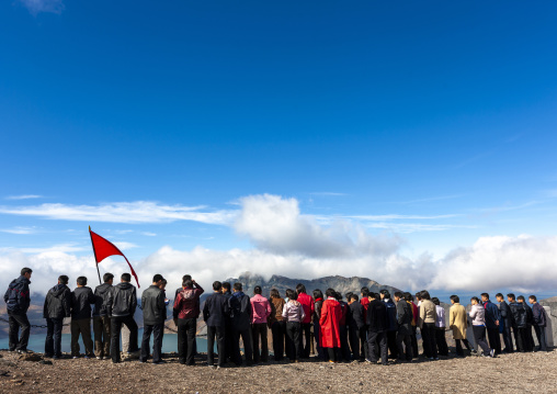 Group of students with red flag in front of lake at mount Paektu, Ryanggang, Mount Paektu, North Korea